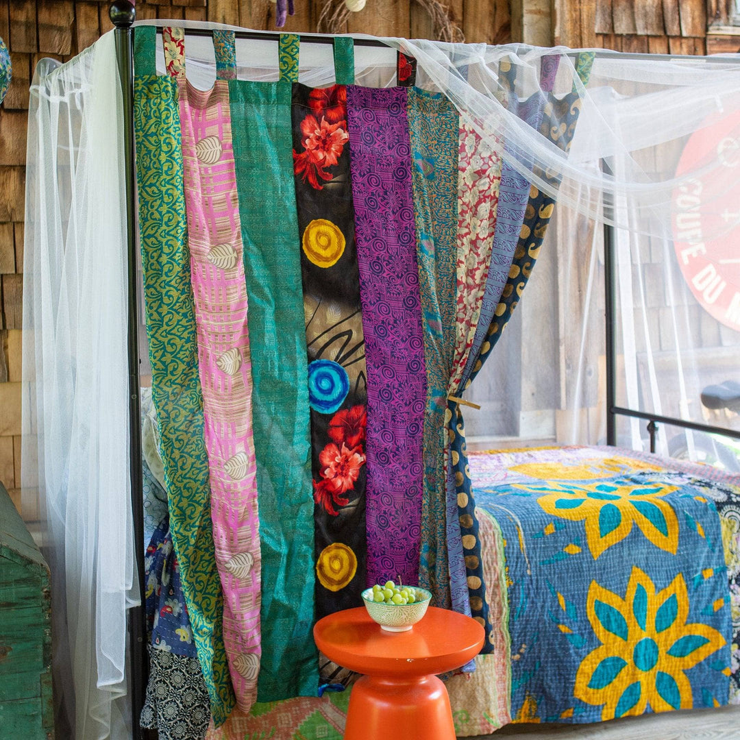 Canopy bed with a one of a kind recycled sari drape hung on it 