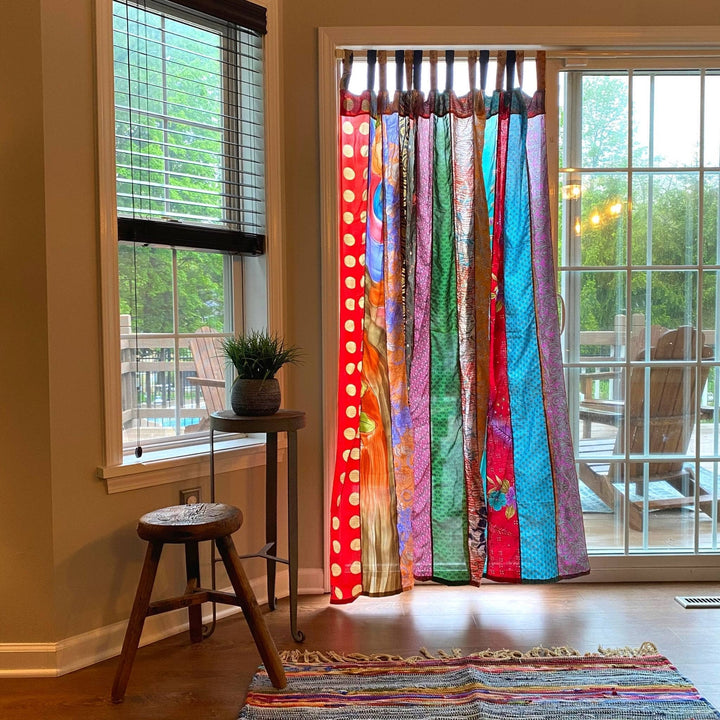 Outdoor sari silk patio curtains hanging in a doorway with the wind blowing behind it 