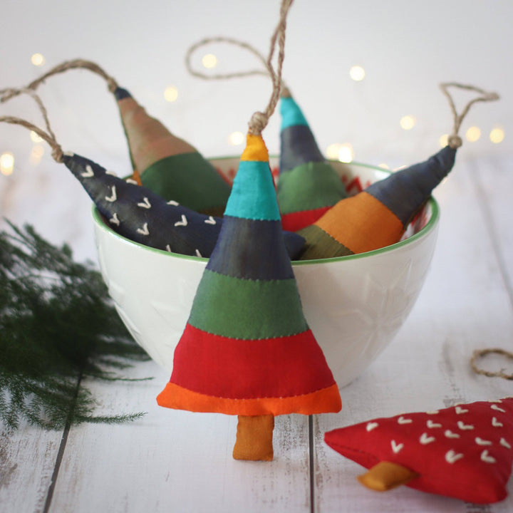 Christmas tree shaped ornaments with trees inside of a bowl on a wooden distressed background