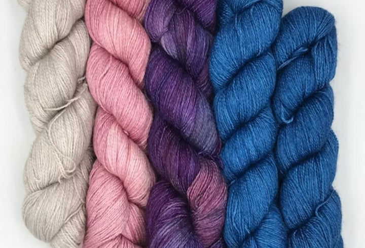 Bundles of yarn in shades of beige, pink, purple, and blue.