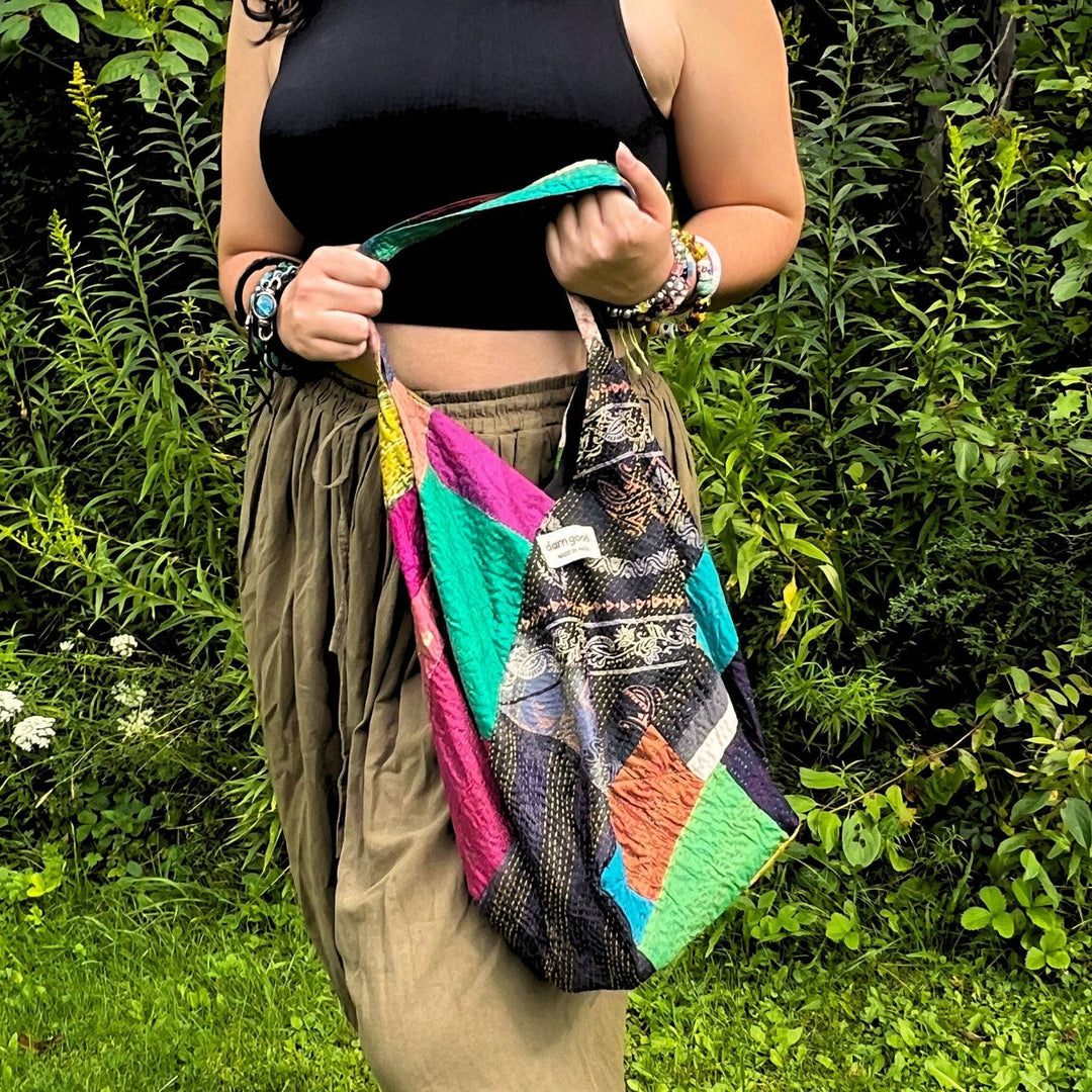 A close up of a woman holding a samosa kantha stitch bag.