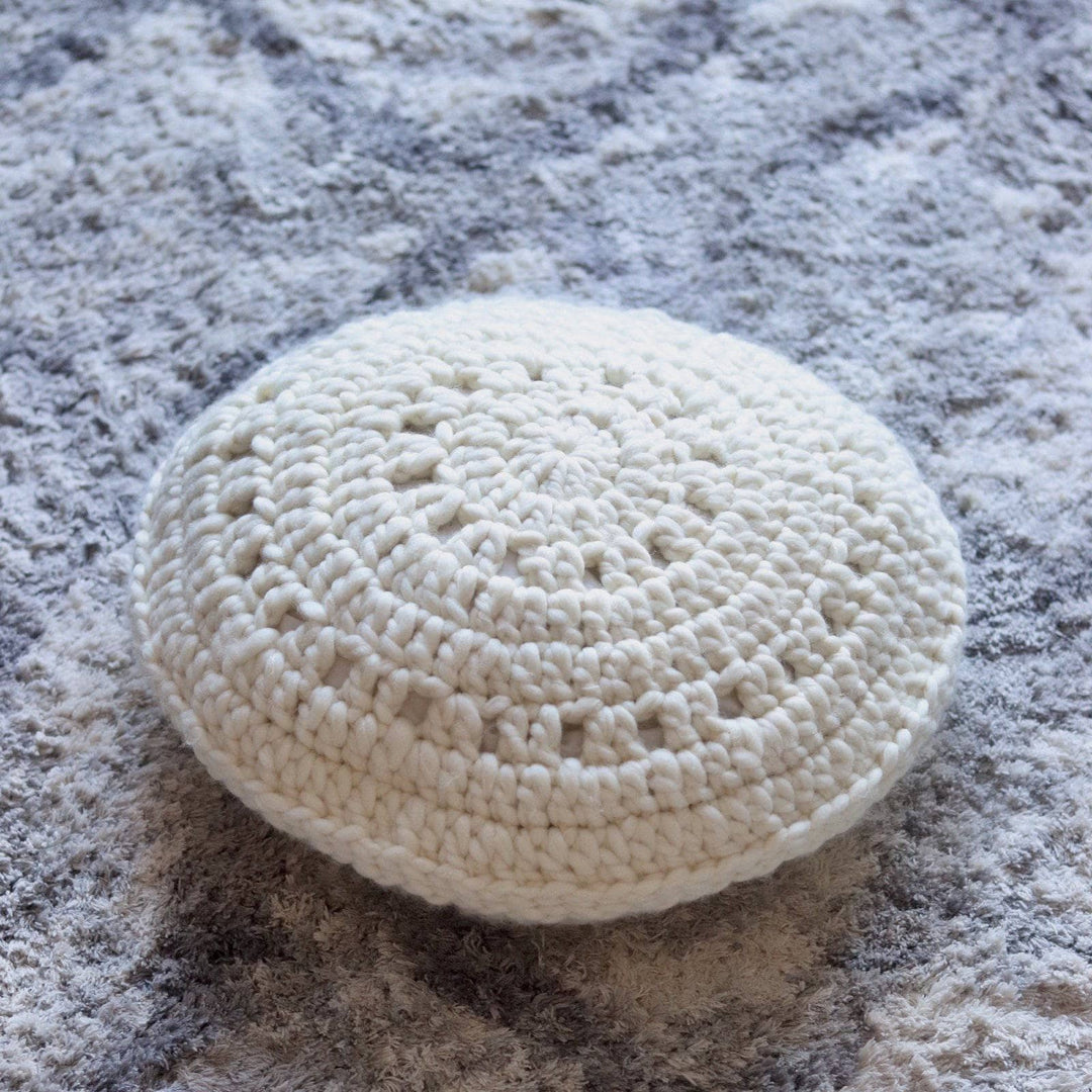 a white pillow on a grey carpet