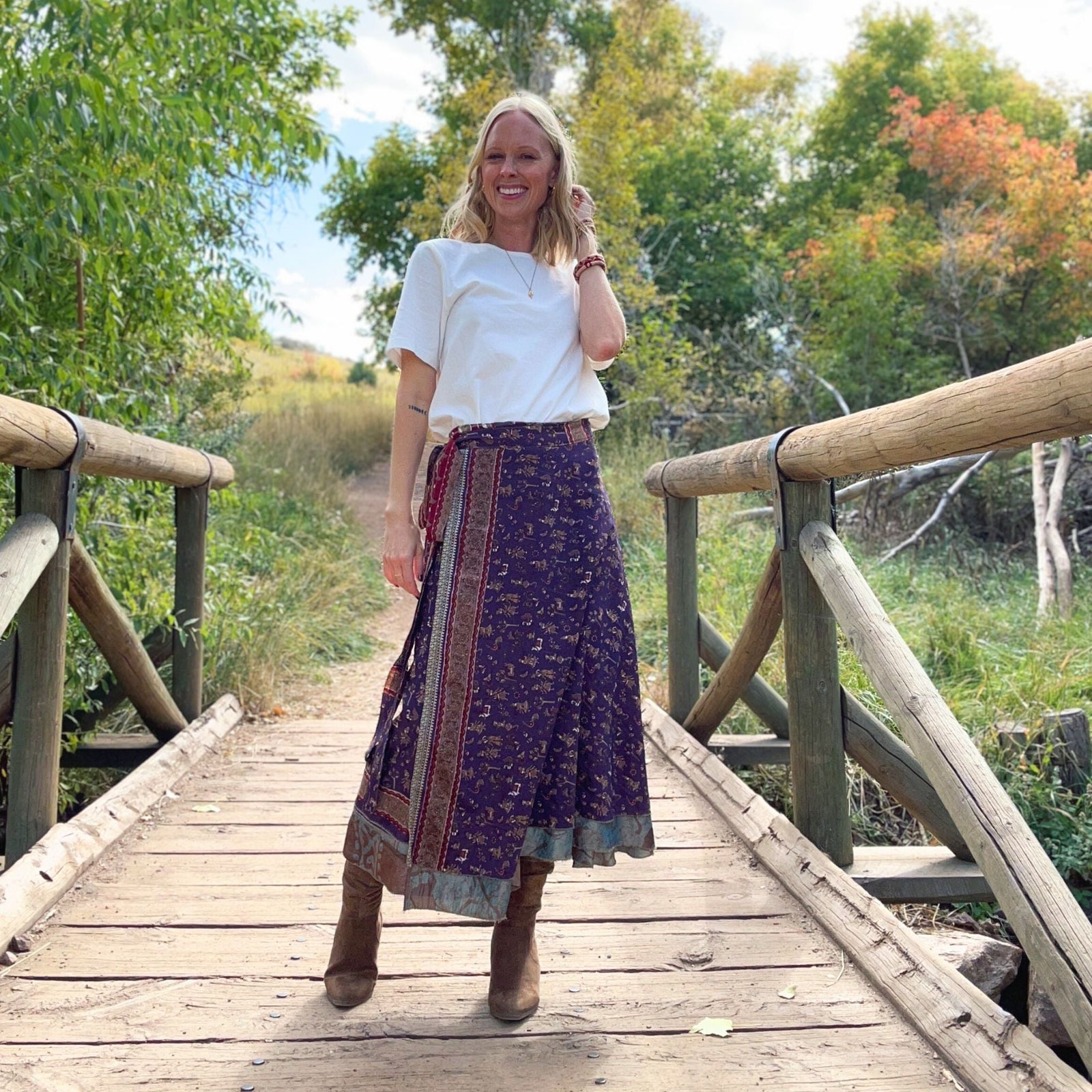 A woman standing on a bridge wearing a bohemian-style skirt and boots.