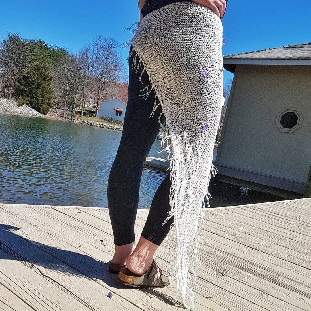 Back view of a woman wearing a white sarong around her waist outside standing next to a lake