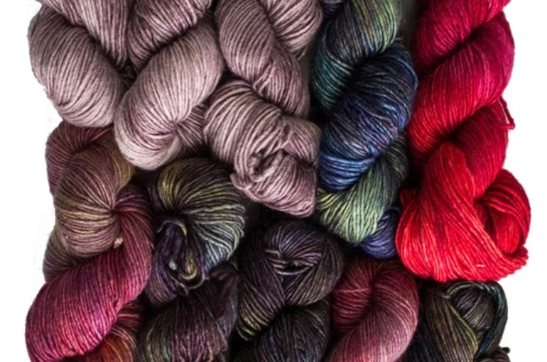 Multicolored yarn skeins with earthy tones of red, brown, and green.