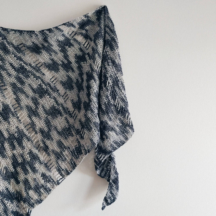 A monochromatic Shawl hanging on a a white wall