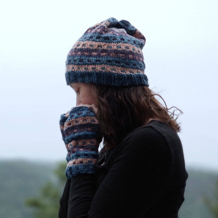 Woman outside wearing a blue, purple and pink matching striped glove and hat set