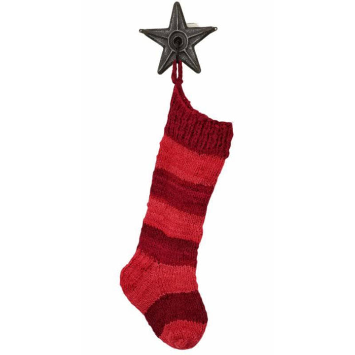 Shaded red stocking hanging on a metal star hook on a white background