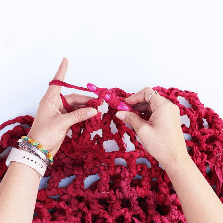 Close up of woman's hands making the summer Nights Chiffon Crochet Shawl on a white background