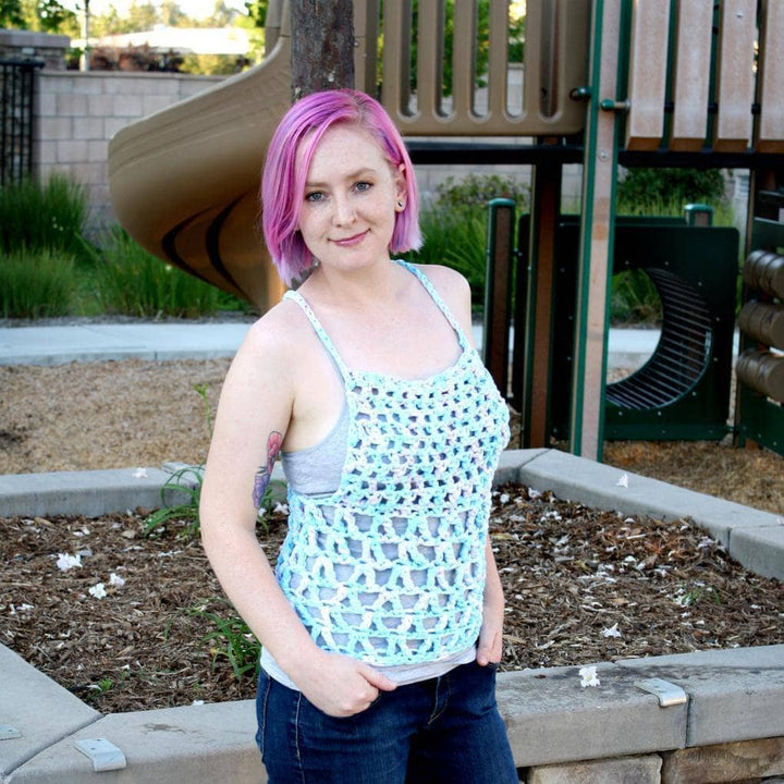 Woman with pink hair wearing The Celia Tank Top in front of a children's playground