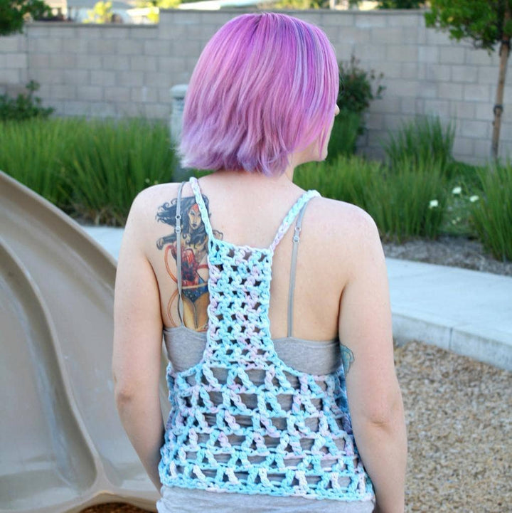 Woman with pink hair wearing The Celia Tank Top in front of a children's playground