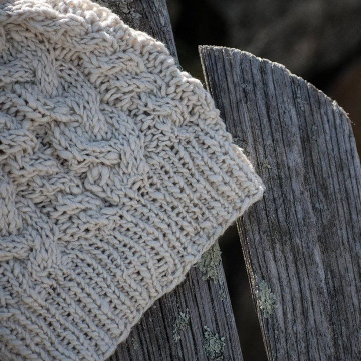 The Magnolia Beanie in Dandelion Poof (white) on a wooden background