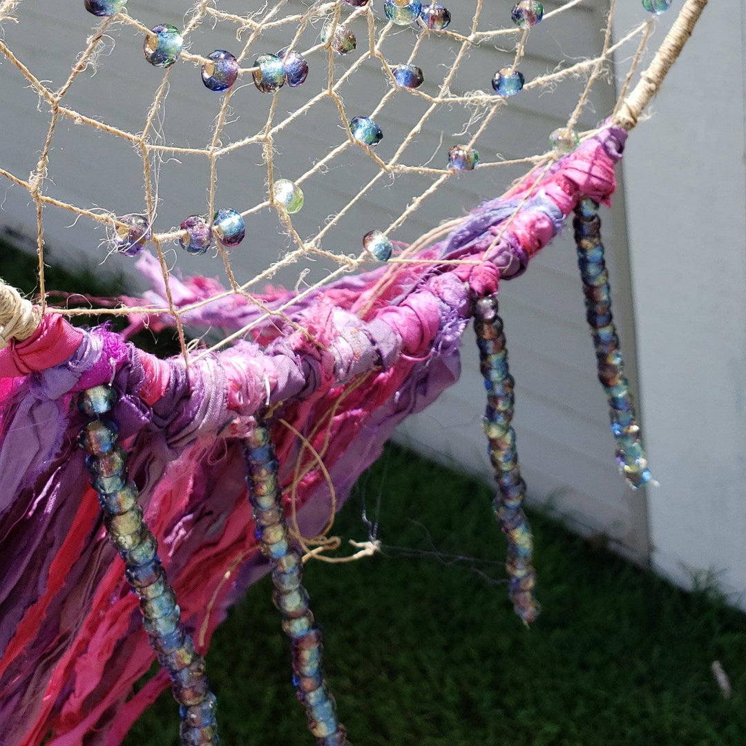 The Simple Dreamcatcher in pinks hung in front of a white wall