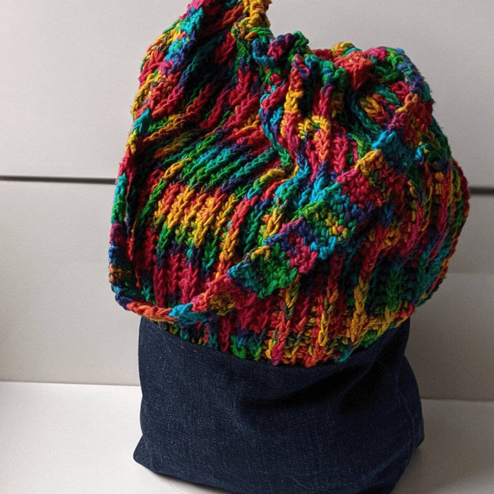 Denim Bag with a rainbow crochet top and handles on a white background