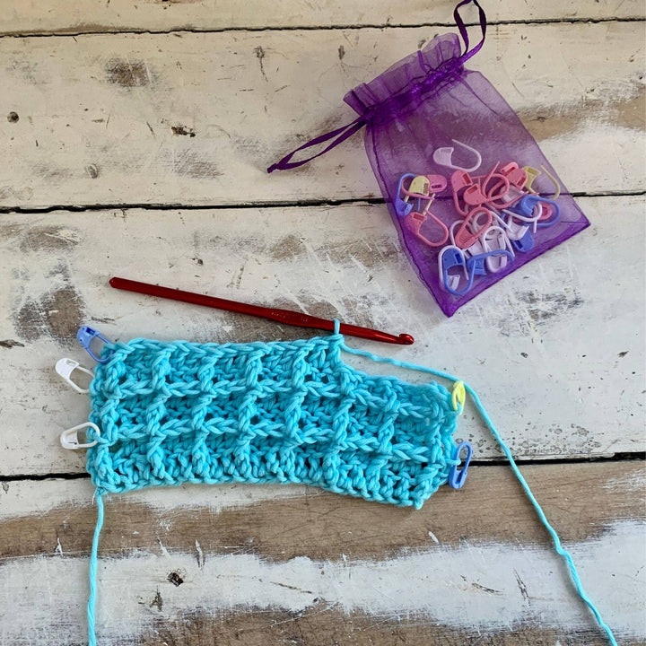 in progress photo of blue crocheted waffle stitch washcloth in front of a white background. 