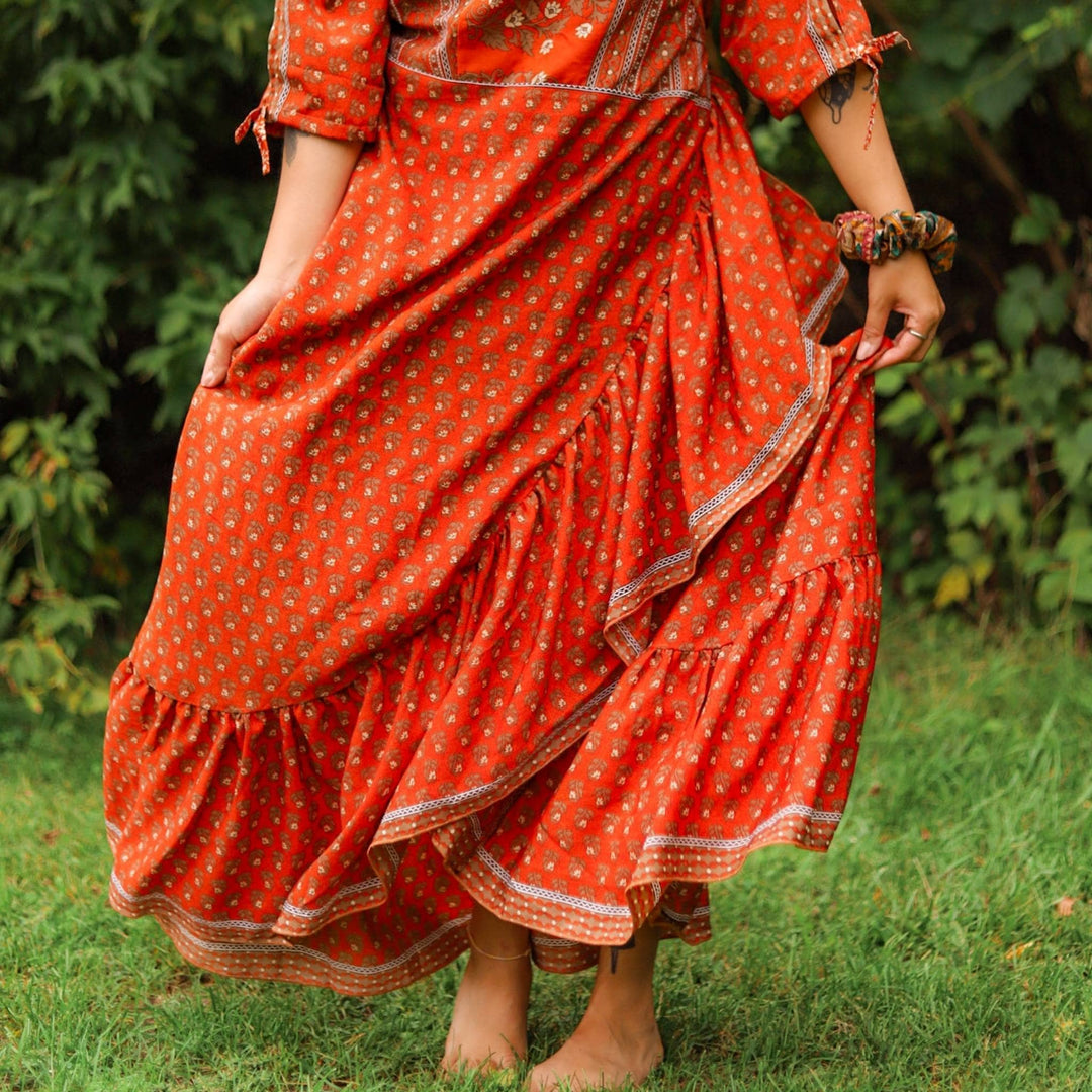 Bottom half of model wearing a red zaria wrap dress while standing in the grass. 