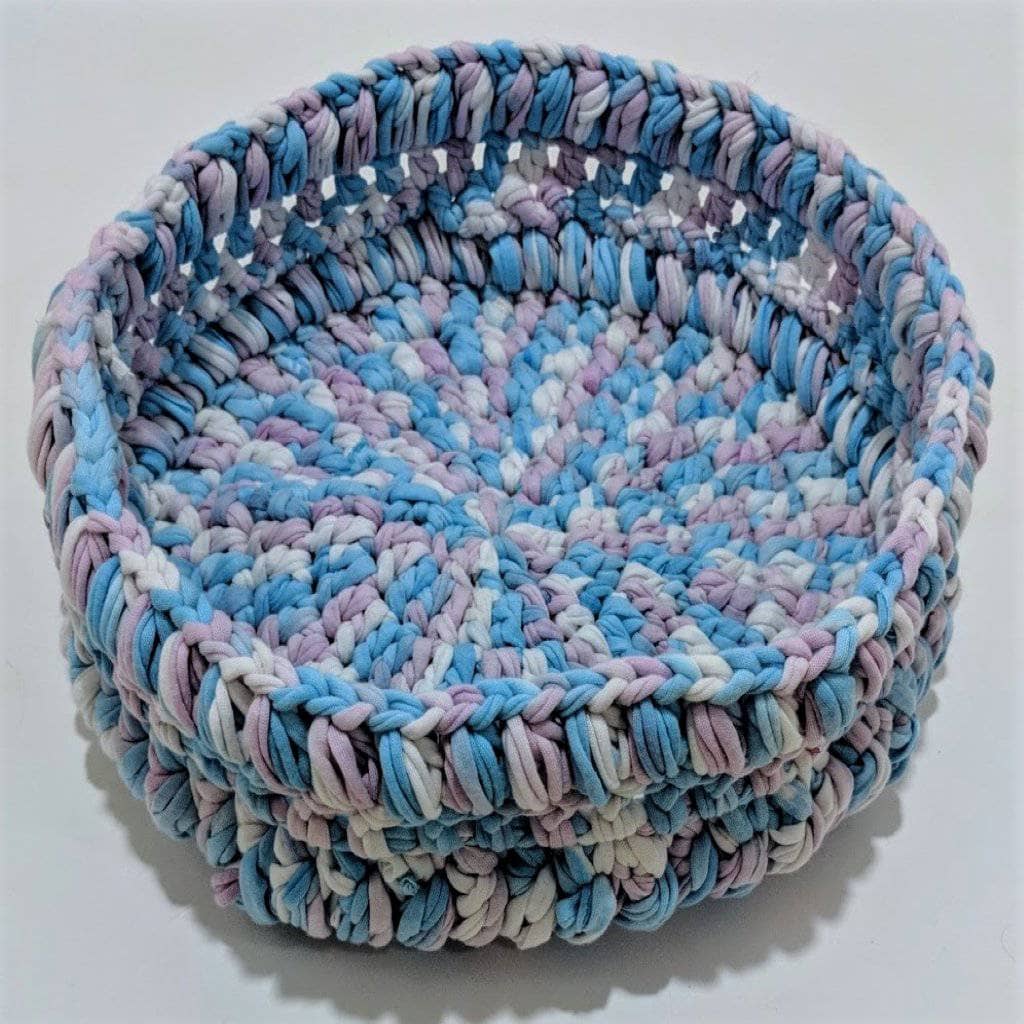 Blue, pink, and white crochet basket on a white background