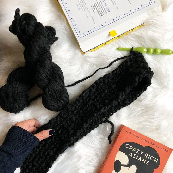 black scarf over a white blanket with books next to it