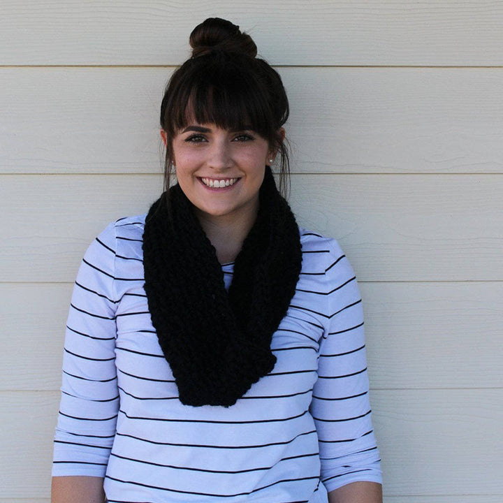 woman with black scarf smiling over a white wall