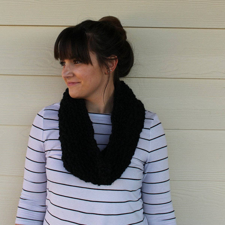 woman with black scarf smiling over a white wall